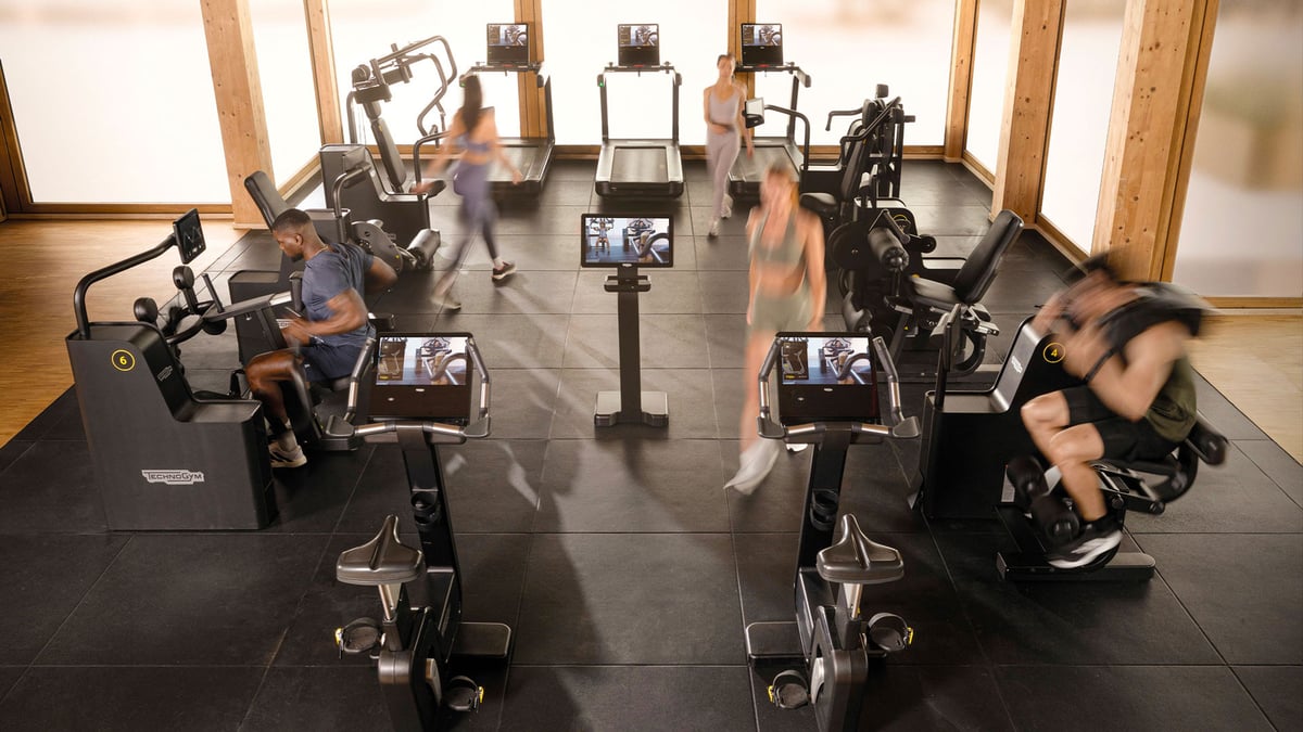 Kuntoilijoita treenaamassa numeroiduilla Biocircuit-laitteilla, keskellä Technogym-kioski.