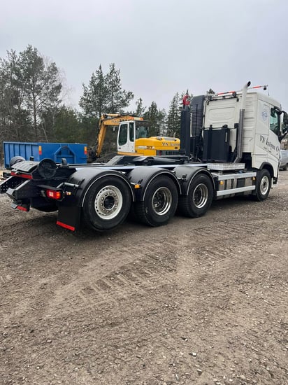 Kuorma-auto jonka takana kaivinkone siirotalavan edessä.